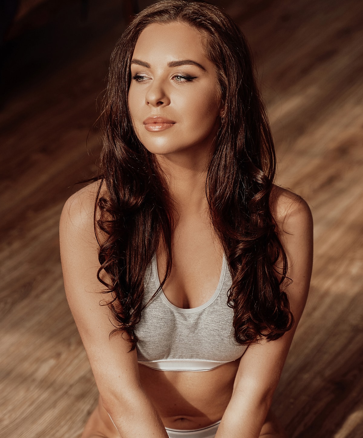 Woman with long hair in sports bra, thoughtful expression.