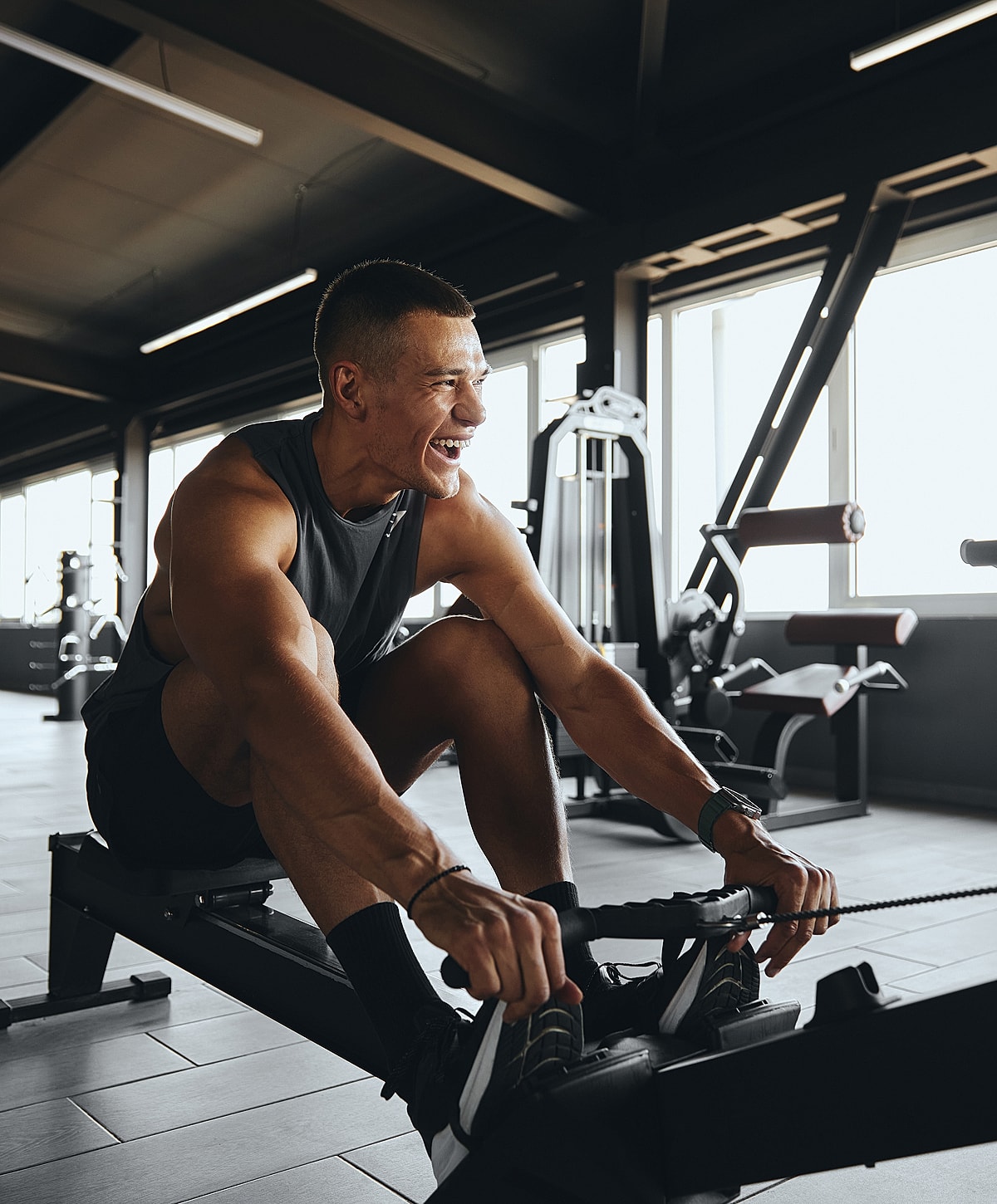 Man exercising on rowing machine, smiling happily.